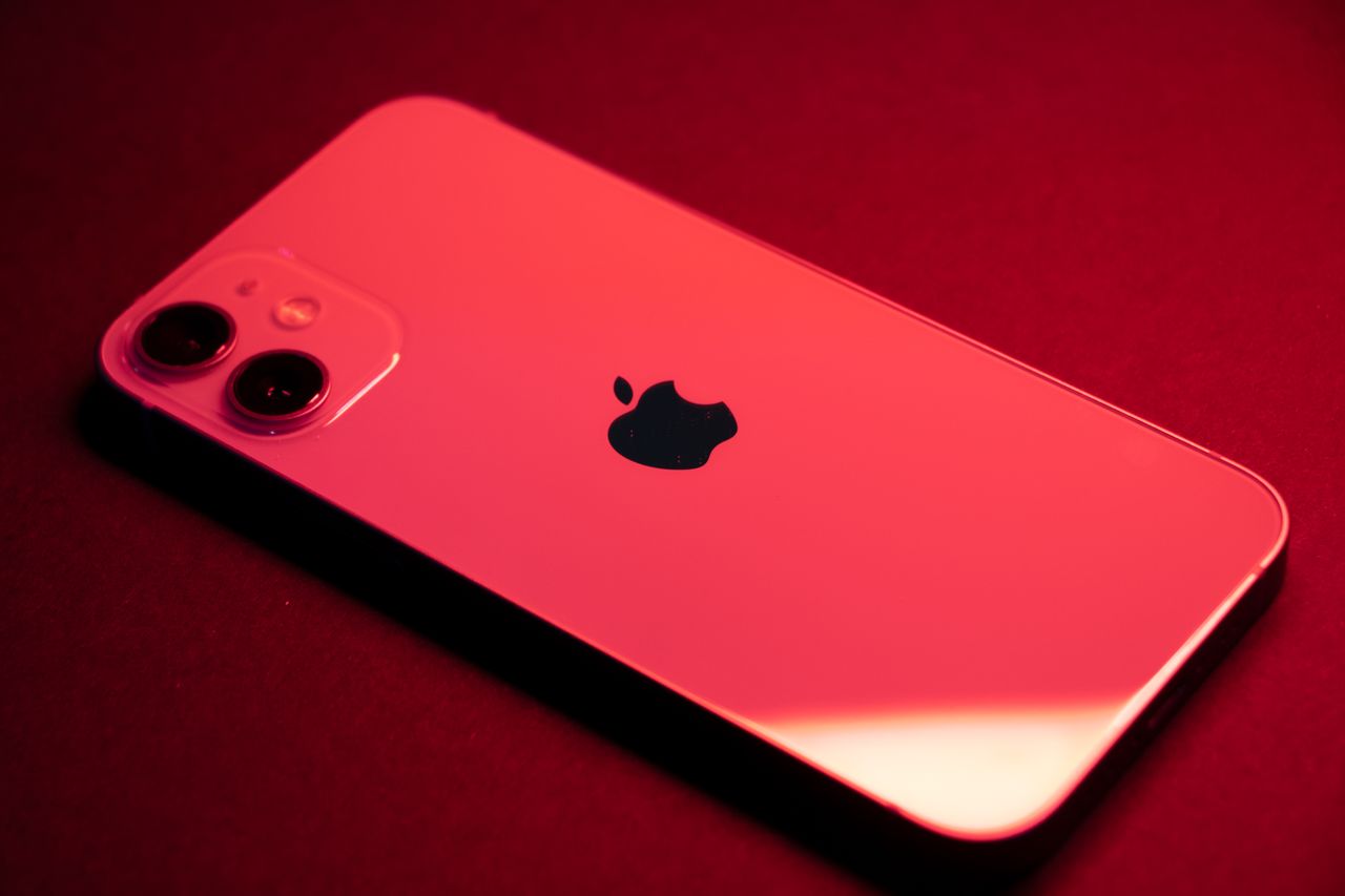 Close-up of a red smartphone with dual lenses on a red backdrop, highlighting sleek design and technology.