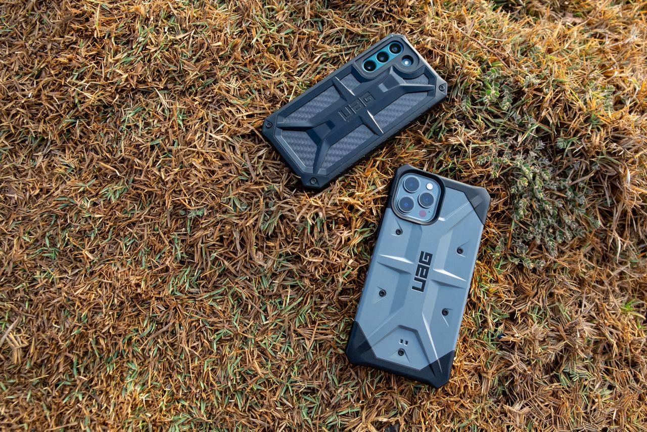 Rugged smartphone cases on grass, showcasing protective designs by UAG. Ideal for outdoor adventures.