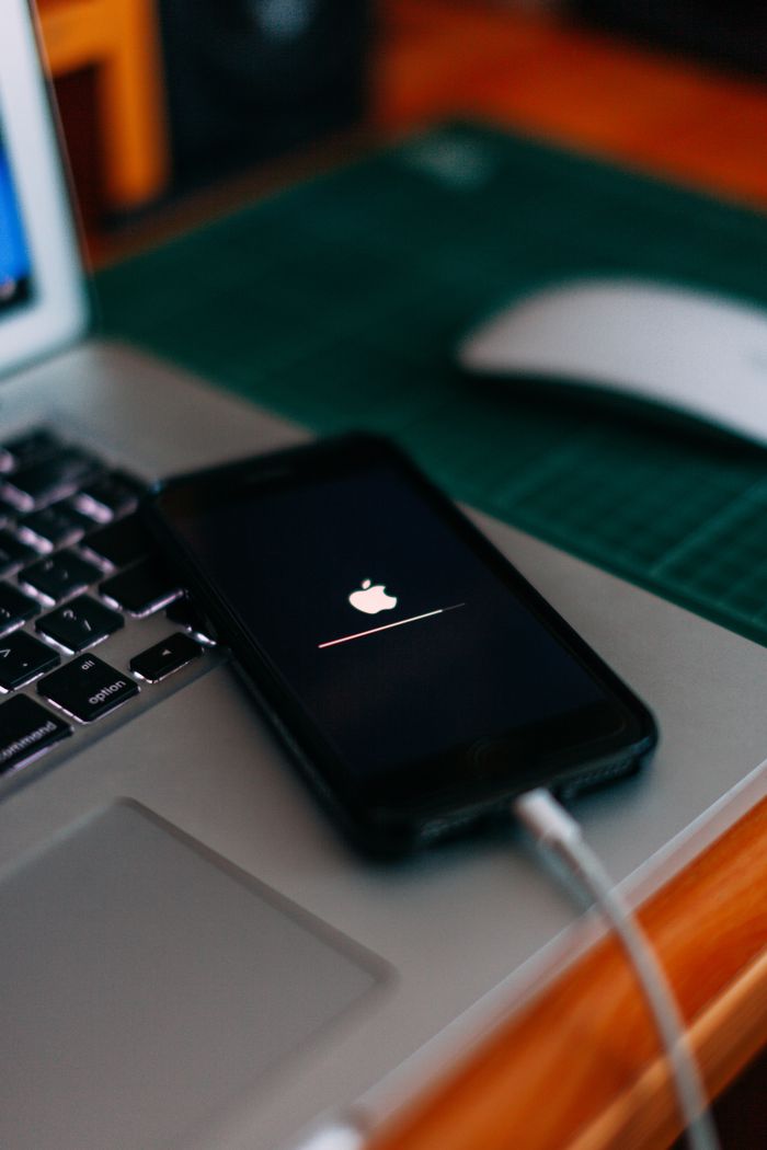 Close-up of a smartphone charging on a laptop. Ideal for tech themes.