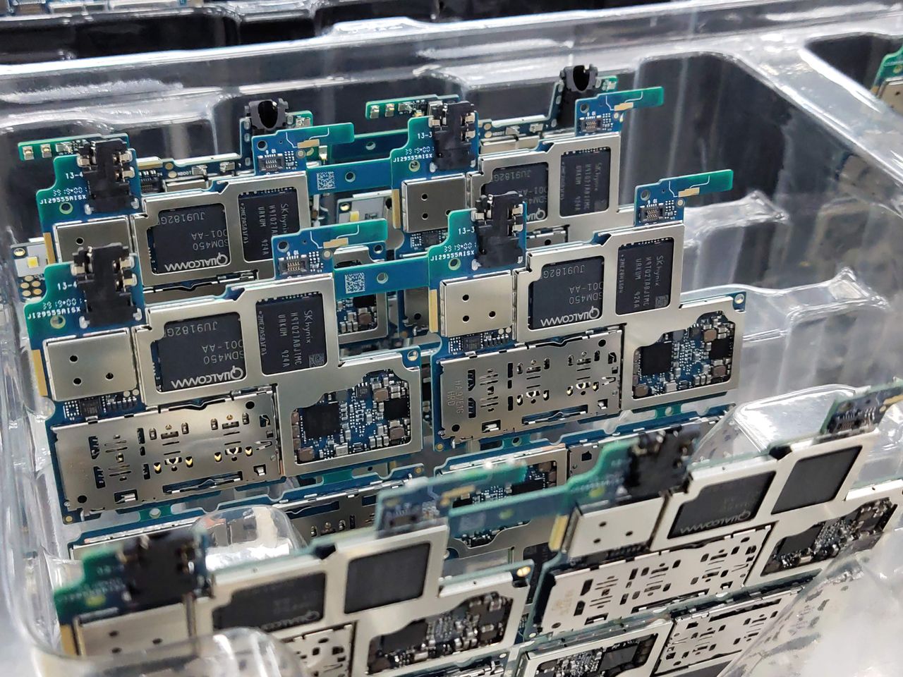 From above of circuit boards of modern smartphones placed in plastic box in electronics factory