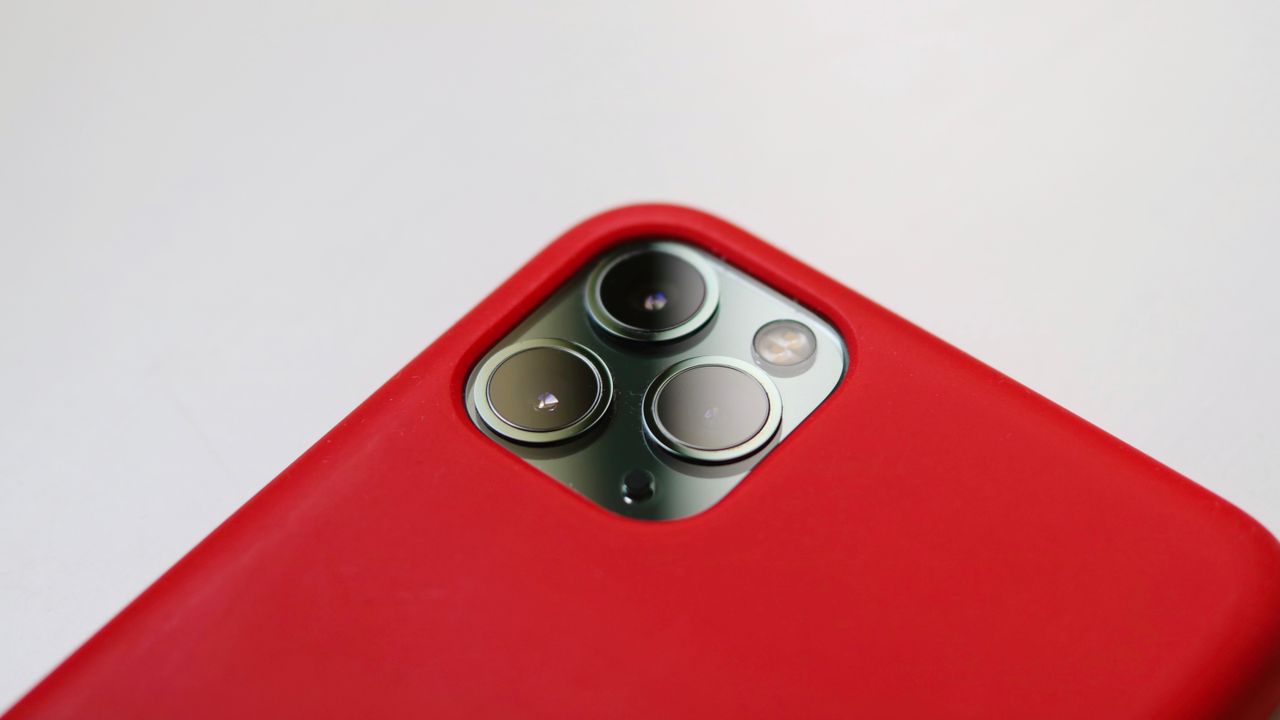 Macro shot of a smartphone camera with a red case, highlighting lens detail.