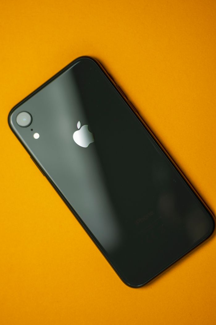 Sleek black smartphone on a vibrant yellow background emphasizing modern technology design.